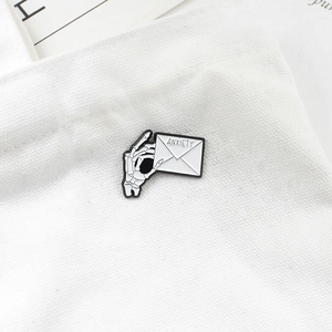 Punk style skeletal hand holding an anxiety letter enamel brooch pin on a canvas bag