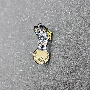 Detailed enamel brooch featuring an astronaut playing saxophone on a meteorite