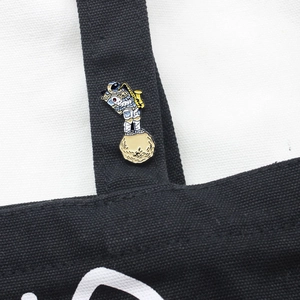 Detailed close-up of astronaut playing saxophone enamel pin on a black canvas bag strap