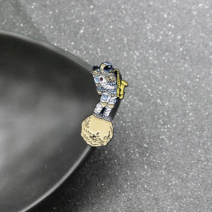 Macro shot of an astronaut enamel pin playing saxophone on a moon surface detail