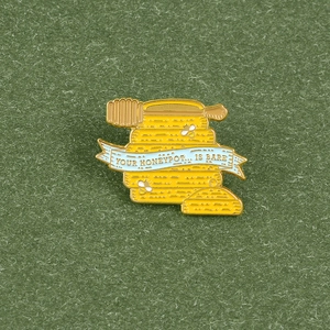 Detail of creative honey pot enamel pin with bees and YOUR HONEYPOT IS BARE slogan