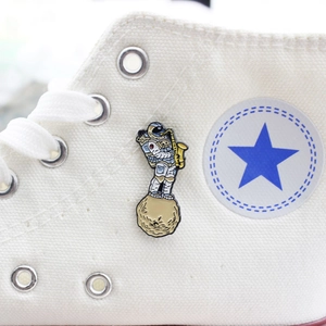 Detail of creative astronaut playing saxophone enamel pin on a white canvas shoe