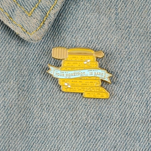 Creative honey pot enamel brooch with busy bee and blue ribbon on denim fabric