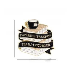 Detail of enamel book and tea cup brooch with text Happiness is a Cup of Tea and a Good Book