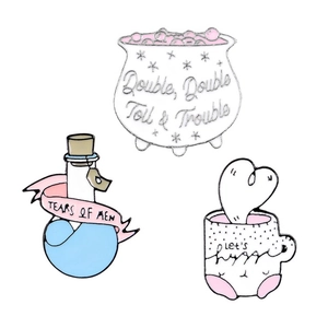 Three creative enamel pins including Witch Cauldron, Tears of Men bottle and Hug Cup