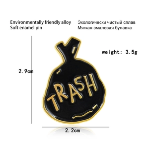 Detail showing TRASH enamel pin dimensions 2.9cm by 2.2cm on white background