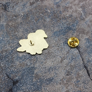 Vue arrière de la broche colombe dorée avec fermoir papillon sur fond de pierre