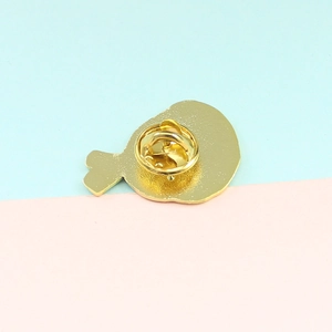 Detail view of a golden metal badge back showing the clutch pin and matte texture