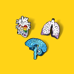 Set of three anatomy enamel pins featuring rainbow heart, purple lungs and blue brain badges
