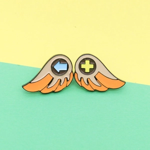 Creative angel wings game controller enamel pins in vibrant orange and yellow with retro D-pad