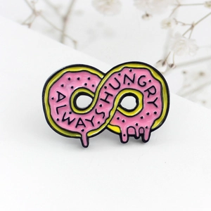 Detail of infinity donut enamel pin with Always Hungry text on floral background