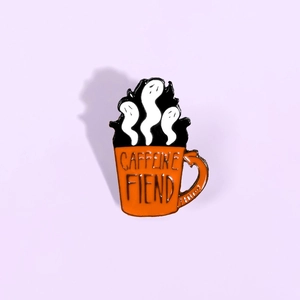 Vue détaillée d'un pin's en émail orange avec des fantômes et texte Caffeine Fiend