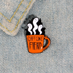 Broche émaillée tasse à café fantôme sur jean bleu montrant un design créatif et élégant