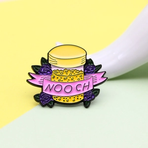 Détail d'une broche en émail 'NOOCH' avec des roses violettes et un ruban rose élégant