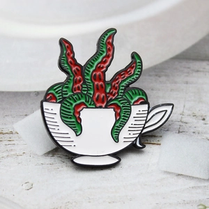 Macro detail of enamel brooch showing surreal succulents in a white creative cup