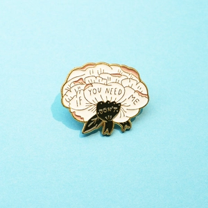 Cream floral enamel brooch with gold edges and If You Need Me text on blue background