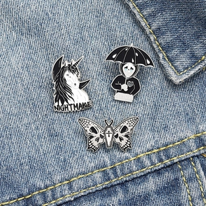 Three gothic enamel pins featuring nightmare unicorn, skull reaper, and butterfly coffin designs