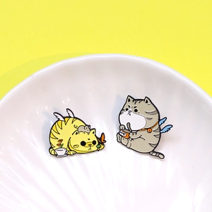 Set di due graziose spille in smalto a forma di gatto con ali su sfondo giallo e vassoio