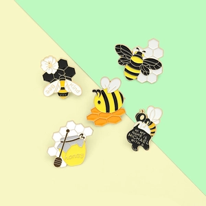 Set of five cute cartoon bee enamel pins with honeycomb and honey jar motifs