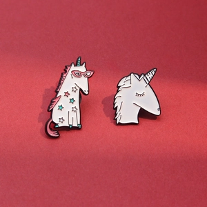 Détail de deux épingles en émail licorne avec motifs d'étoiles sur fond rouge texturé