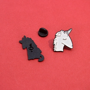 Détail d'un pin's licorne en émail avec fermoir en caoutchouc noir sur fond rouge vif