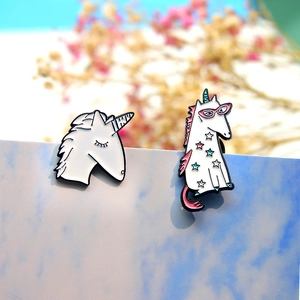 Détail de deux pin's licorne en émail avec étoiles colorées sur fond de papier bleu