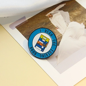 Badge en émail bleu avec illustration de livres et texte I READ THE FUCKING BOOK