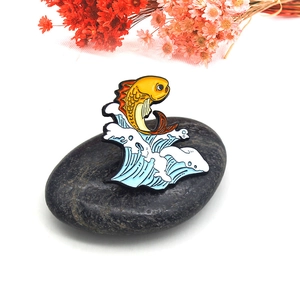 Épingle émaillée créative avec carpe koi jaune sautant sur des vagues bleues sur pierre