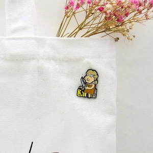 Kreative Emaille-Anstecknadel mit B.U.Y-Design auf weißer Segeltuchtasche mit Blumen