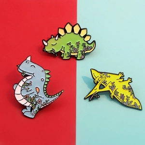 Trois pin's dinosaures colorés en émail avec motifs floraux sur fond rouge et bleu