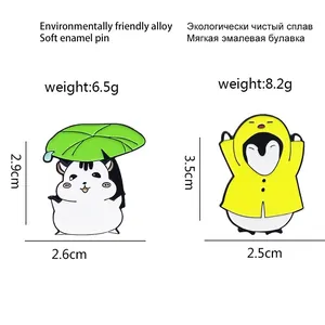 Cute enamel pins featuring a hamster with a leaf umbrella and a penguin in a yellow raincoat