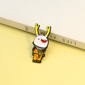 Detailed close-up of a creative yellow cartoon deer enamel pin on a soft lifestyle background