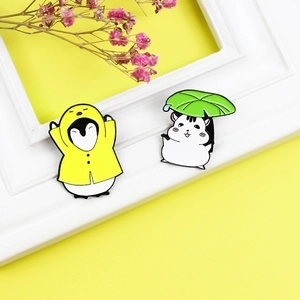 Cute enamel pin set featuring a penguin in yellow raincoat and hamster with leaf umbrella