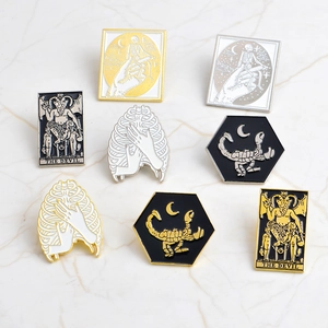 Gothic enamel pin set with skull, scorpion, and tarot motifs on marble background