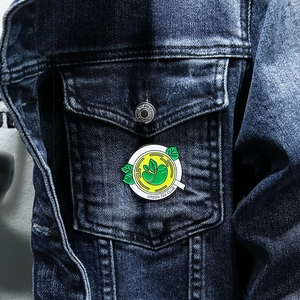 Green Tea Club enamel pin with leaf character displayed on a blue denim jacket pocket