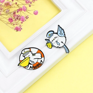 Cartoon enamel bird brooch set with sailor pelican and captain badge on yellow backdrop