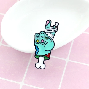 Broche émaillée créative main de zombie geste paix avec peau verte et bandage