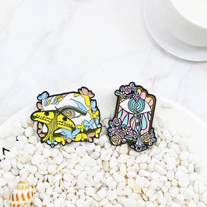 Lot de broches émaillées surréalistes avec papillons et yeux sur table en marbre