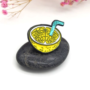 Creative lemon brain enamel pin with straw design on a pebble and floral background