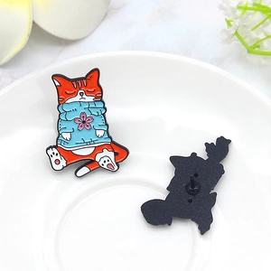 Süße Emaille-Brosche mit orangefarbener Katze im blauen Kirschblütenpullover auf Porzellan