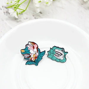 Creative enamel wolf and shark flower pins in a white ceramic dish with floral accents