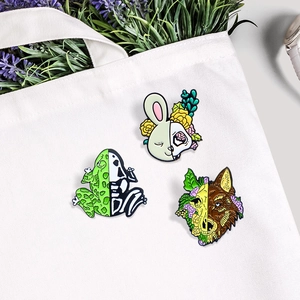 Three enamel pins featuring frog, rabbit, and wolf half-skeleton designs on a canvas bag
