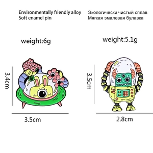 Detail showing two cartoon enamel pins with spaceship and robot designs on white background