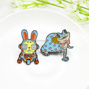 Robot rabbit and heart frog enamel pins set on a white ceramic tray with flowers
