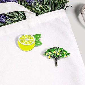 Cartoon lemon and fruit tree enamel brooches pinned on white canvas bag in summer vibes