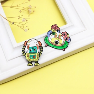 Creative enamel pins featuring space rabbit and yellow alien robot on yellow background