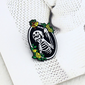 Broche gothique en émail avec crâne, fleurs jaunes et cloche dans un cadre ovale
