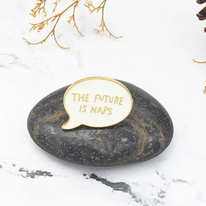 Minimalist enamel speech bubble brooch with The Future is Naps quote on a dark pebble