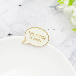 Minimalist enamel speech bubble pin with The Future Is Naps text on a ceramic plate