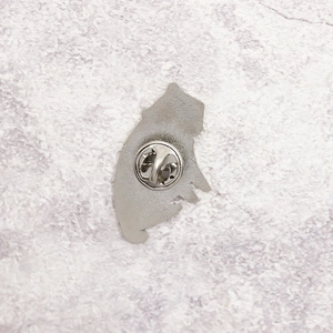 Silver metal badger pin back with standard butterfly clutch fastener on purple background